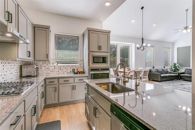 a kitchen with stainless steel appliances a sink a stove and cabinets