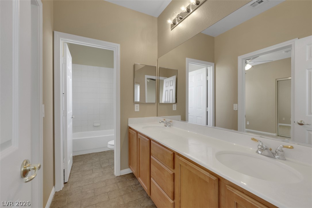 10328 Hawk Ravine Street Las Vegas, NV 89178 - Photo 32 of 55 Double vanity with ample counter space and warm-toned cabinetry defines this inviting bathroom.