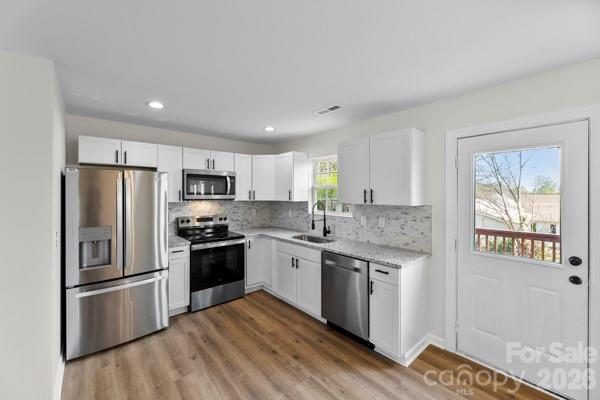 808 3rd Street Kings Mountain, NC 28086 - Photo 11 of 24 a kitchen with stainless steel appliances granite countertop a stove a sink dishwasher a refrigerator and white cabinets with wooden floor