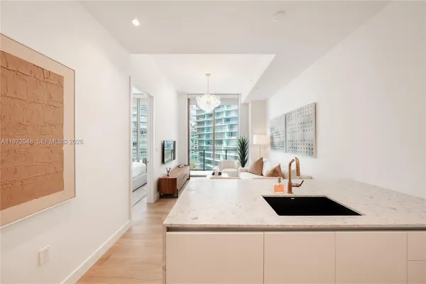 a kitchen with a sink a counter and a living room view