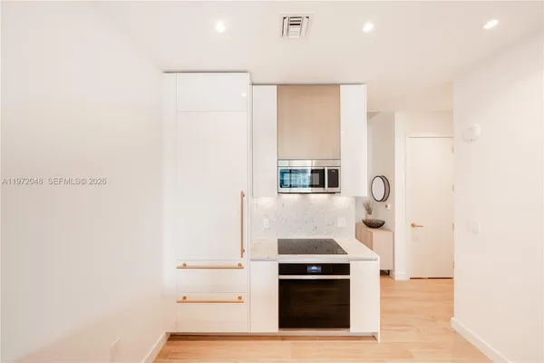 a kitchen with stainless steel appliances a stove and white cabinets