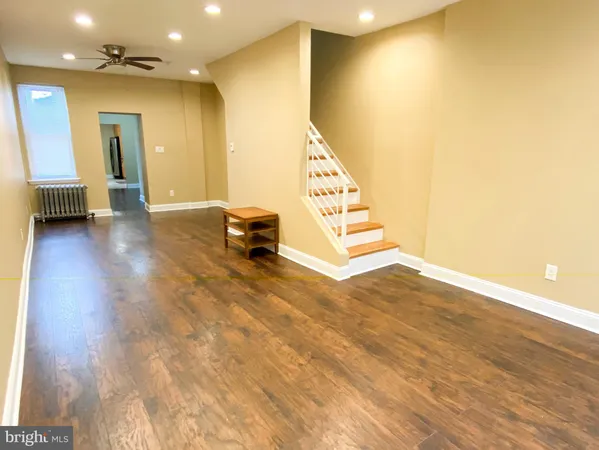 a view of an empty room with stairs and a living room