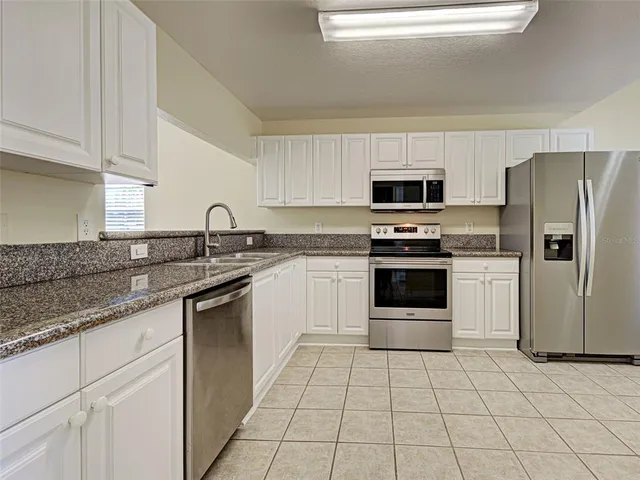 a kitchen with white cabinets and refrigerator