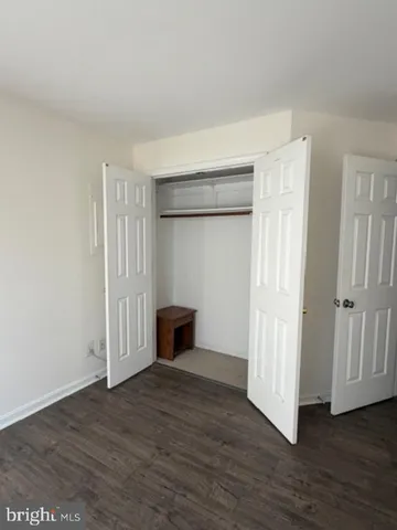 a view of an empty room with wooden floor and closet