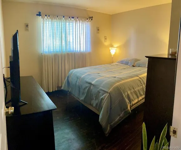 a bedroom with a bed and a flat tv screen on dresser