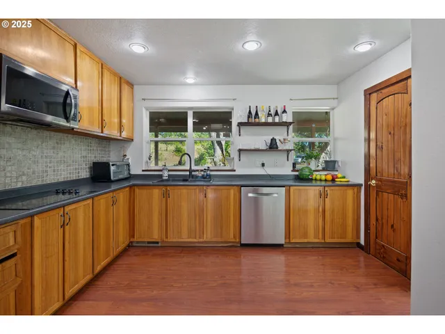 a kitchen with stainless steel appliances granite countertop a refrigerator a sink dishwasher a stove with wooden cabinets and floor