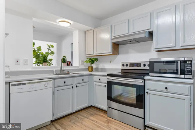 a kitchen with cabinets stainless steel appliances and wooden floor