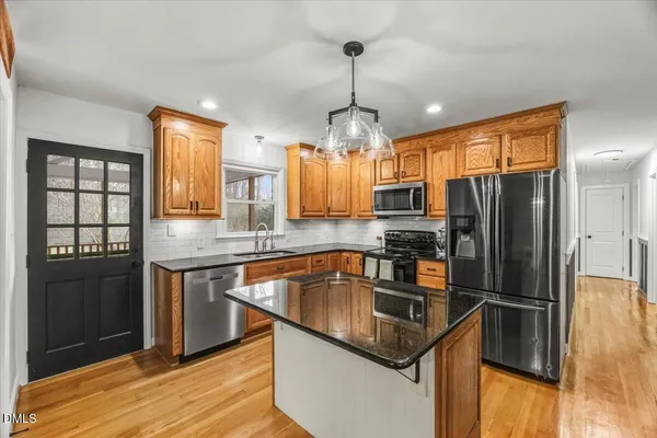 a kitchen with granite countertop a refrigerator and wooden floor