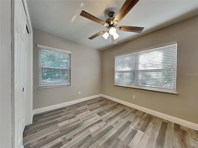 a view of an empty room with wooden floor and a window