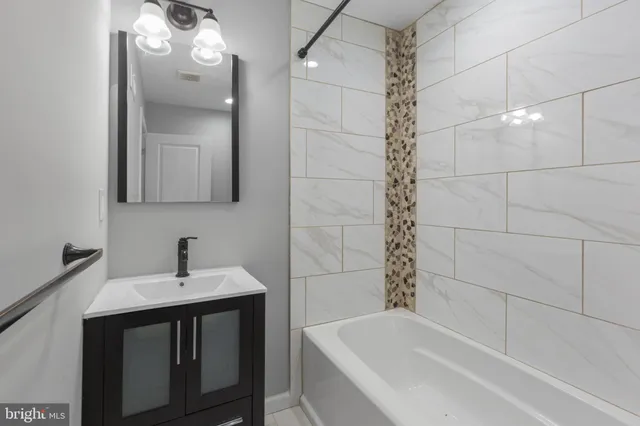 a white bath tub sitting next to a white sink and vanity