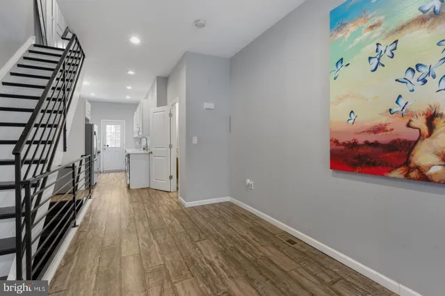 a view of a hallway with wooden floor and a bathroom