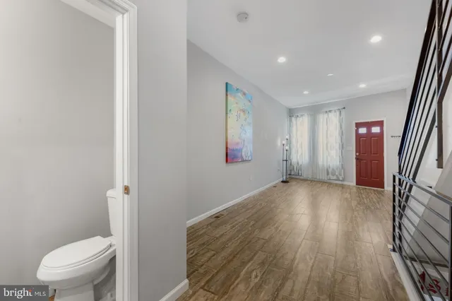 a view of a hallway with wooden floor and a toilet