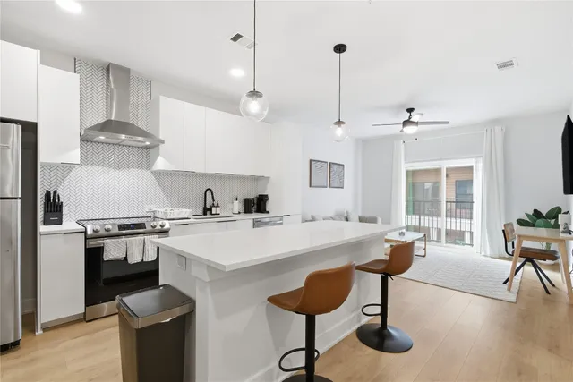 a open kitchen with stainless steel appliances granite countertop a stove a refrigerator a sink a dining table and chairs with wooden floor