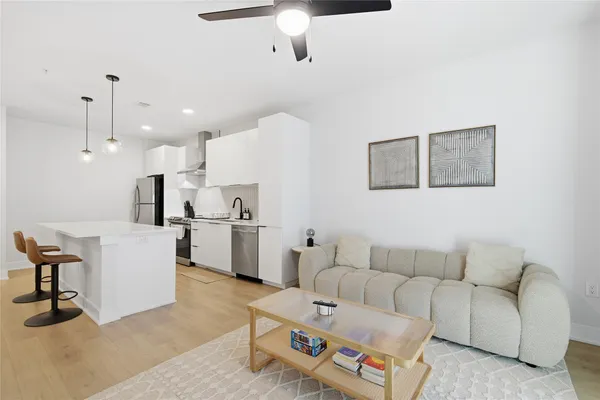 a large kitchen with a large counter top a sink stainless steel appliances and cabinets