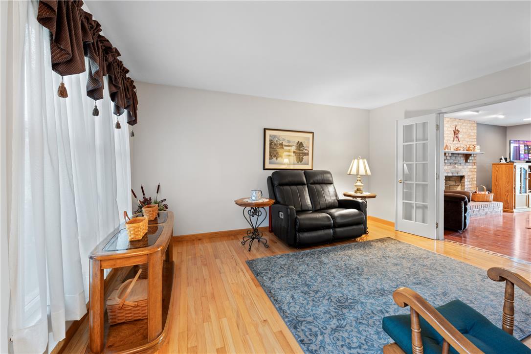 4568 Greenfield Road Bethlehem, PA 18017 - Photo 5 of 59 Warm hardwood floors and abundant natural light create a welcoming living space, opening to an adjoining room with a stone fireplace.