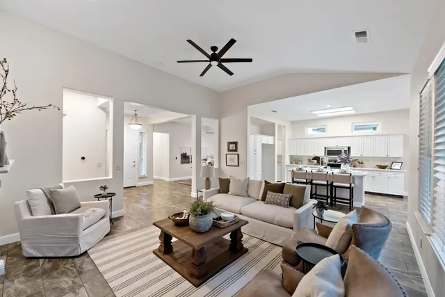 a living room with furniture kitchen view and a chandelier