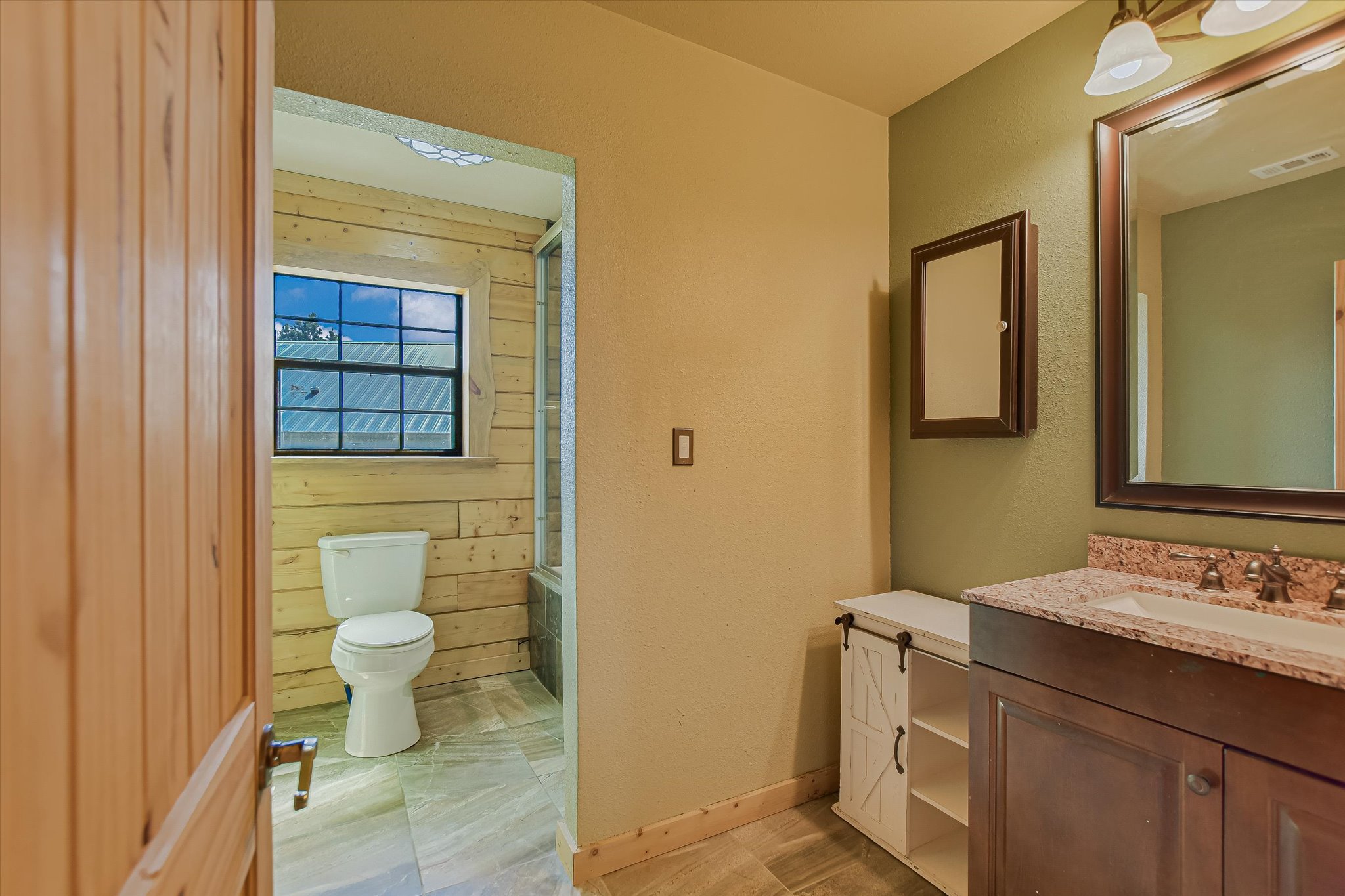 218 Cardinal Loop Paige, TX 78659 - Photo 15 of 22 A well-appointed bathroom features a wooden vanity with a stone countertop, framed mirror, and warm lighting.