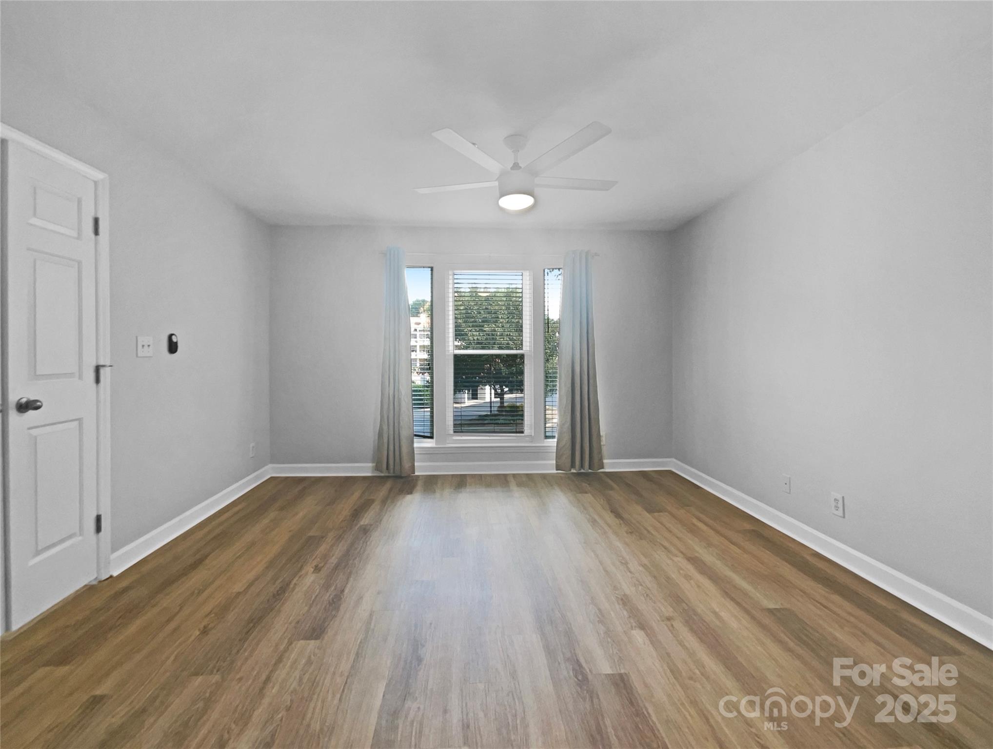 17931 Kings Point Drive, Unit G Cornelius, NC 28031 - Photo 11 of 20 a view of an empty room with wooden floor and a window