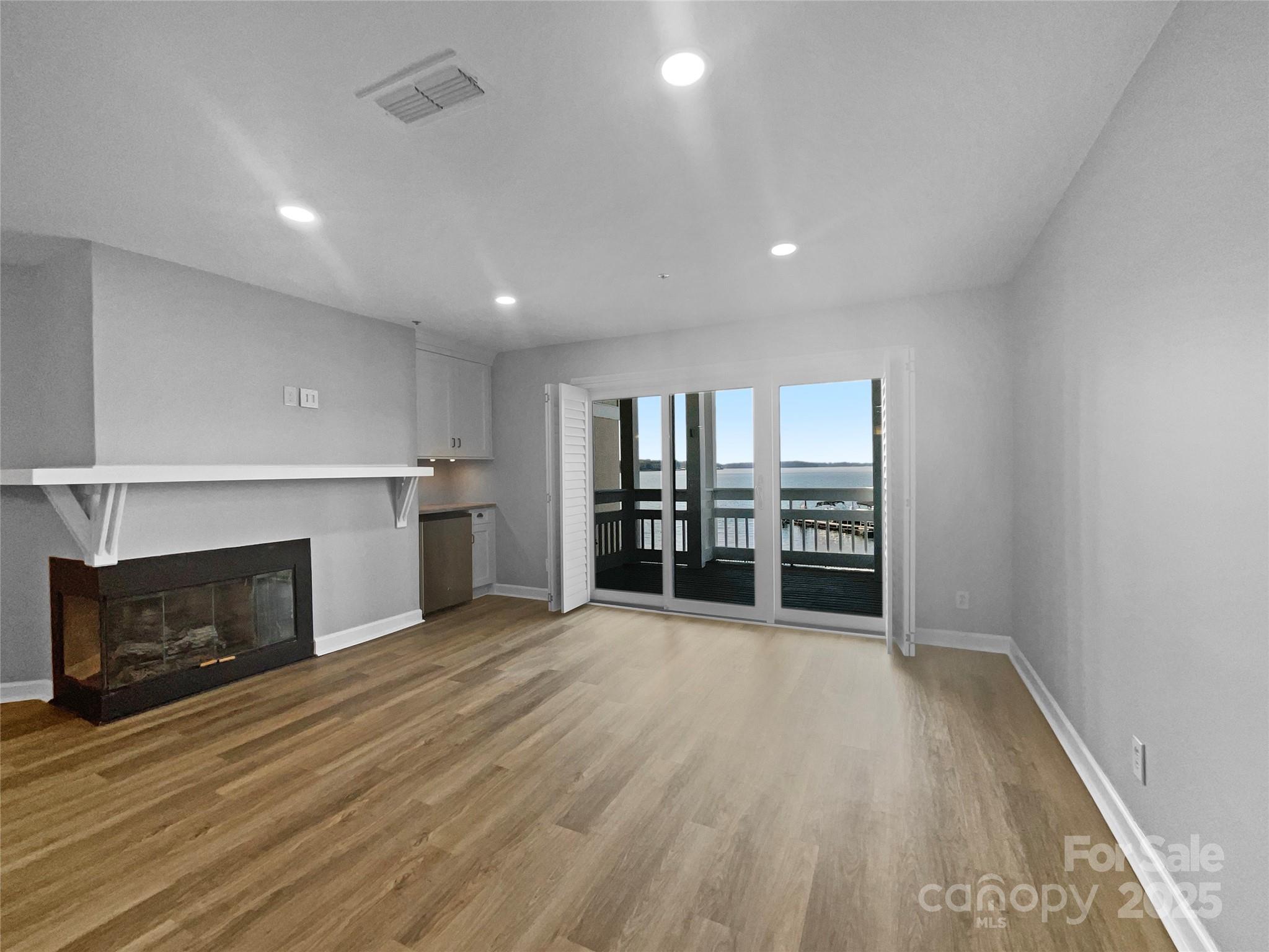 17931 Kings Point Drive, Unit G Cornelius, NC 28031 - Photo 4 of 20 a view of an empty room with wooden floor fireplace and a window