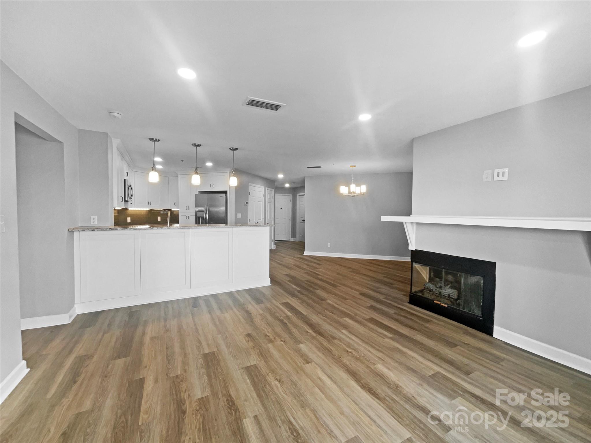 17931 Kings Point Drive, Unit G Cornelius, NC 28031 - Photo 8 of 20 a view of a living room a kitchen with a fireplace and wooden floor