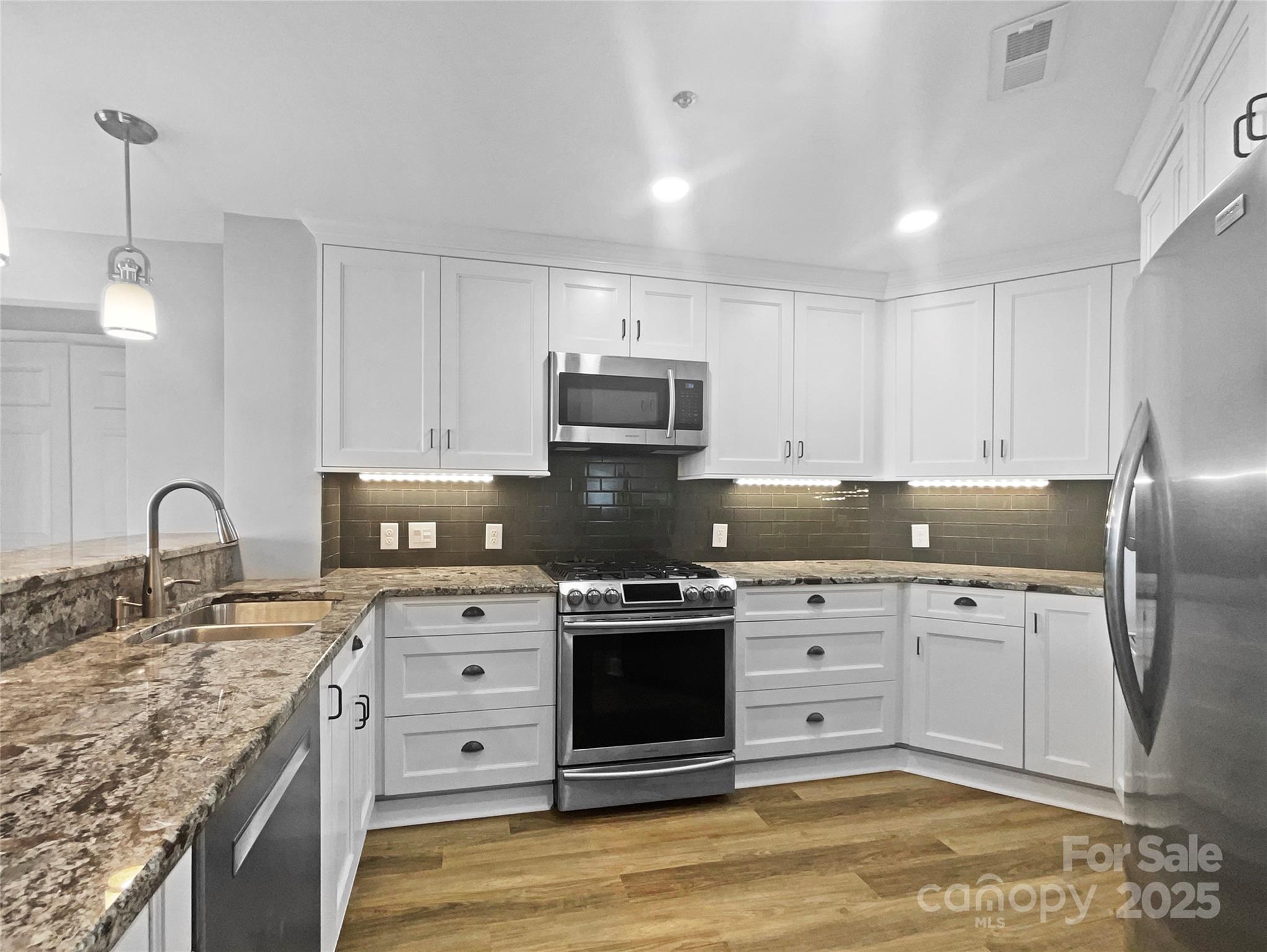 17931 Kings Point Drive, Unit G Cornelius, NC 28031 - Photo 9 of 20 a kitchen with stainless steel appliances granite countertop a stove sink and cabinets
