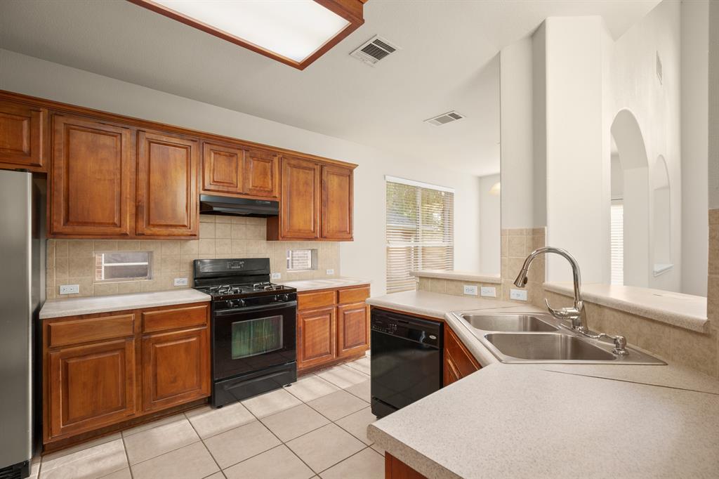 10105 Wind Cave Trail Austin, TX 78747 - Photo 6 of 23 Kitchen featuring abundant wood cabinetry, a gas range with an overhead vent, and a double basin sink