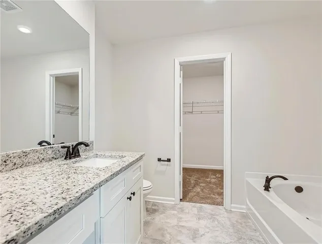 a bathroom with a granite countertop sink a mirror and a bathtub