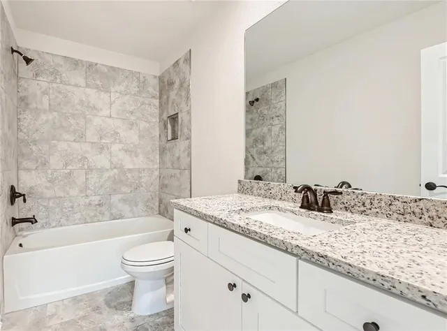 a bathroom with a granite countertop sink a toilet and bathtub