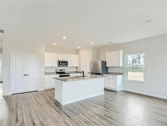 a kitchen with stainless steel appliances a stove top oven a sink dishwasher and a refrigerator with wooden floor