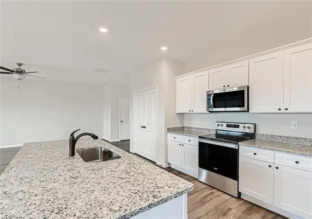 a kitchen with stainless steel appliances granite countertop a sink a stove and a refrigerator