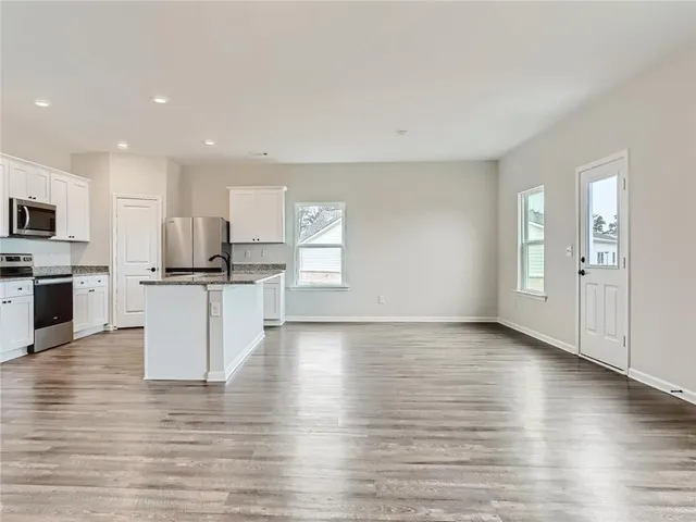 a view of kitchen with granite countertop stainless steel appliances refrigerator sink and cabinets
