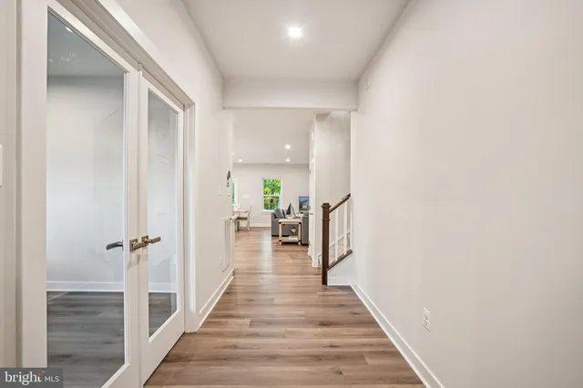 a view of a hallway with wooden floor and a living space