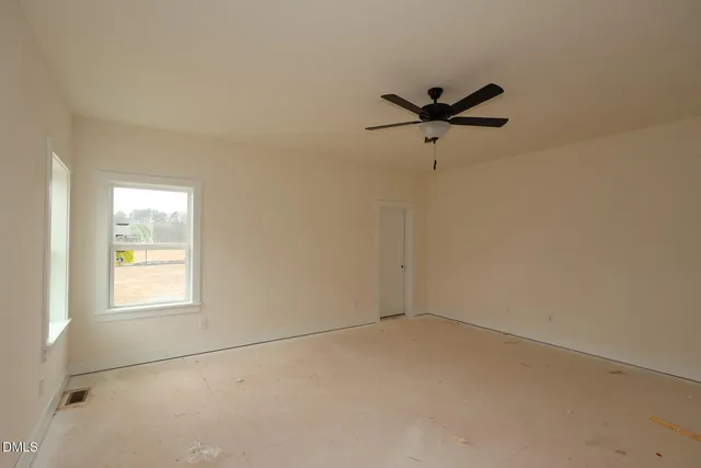 an empty room with a window and a ceiling fan