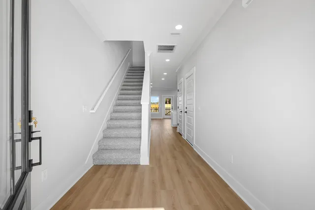a view of a hallway with wooden floor and staircase