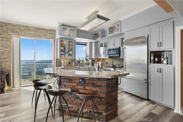 a kitchen with stainless steel appliances granite countertop a refrigerator a stove a sink a dining table and chairs with wooden floor