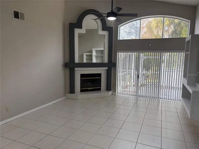 an empty room with wooden floor fireplace and windows