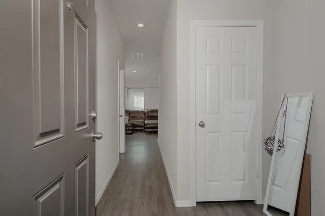 a view of a hallway with a hardwood floor and a bathroom