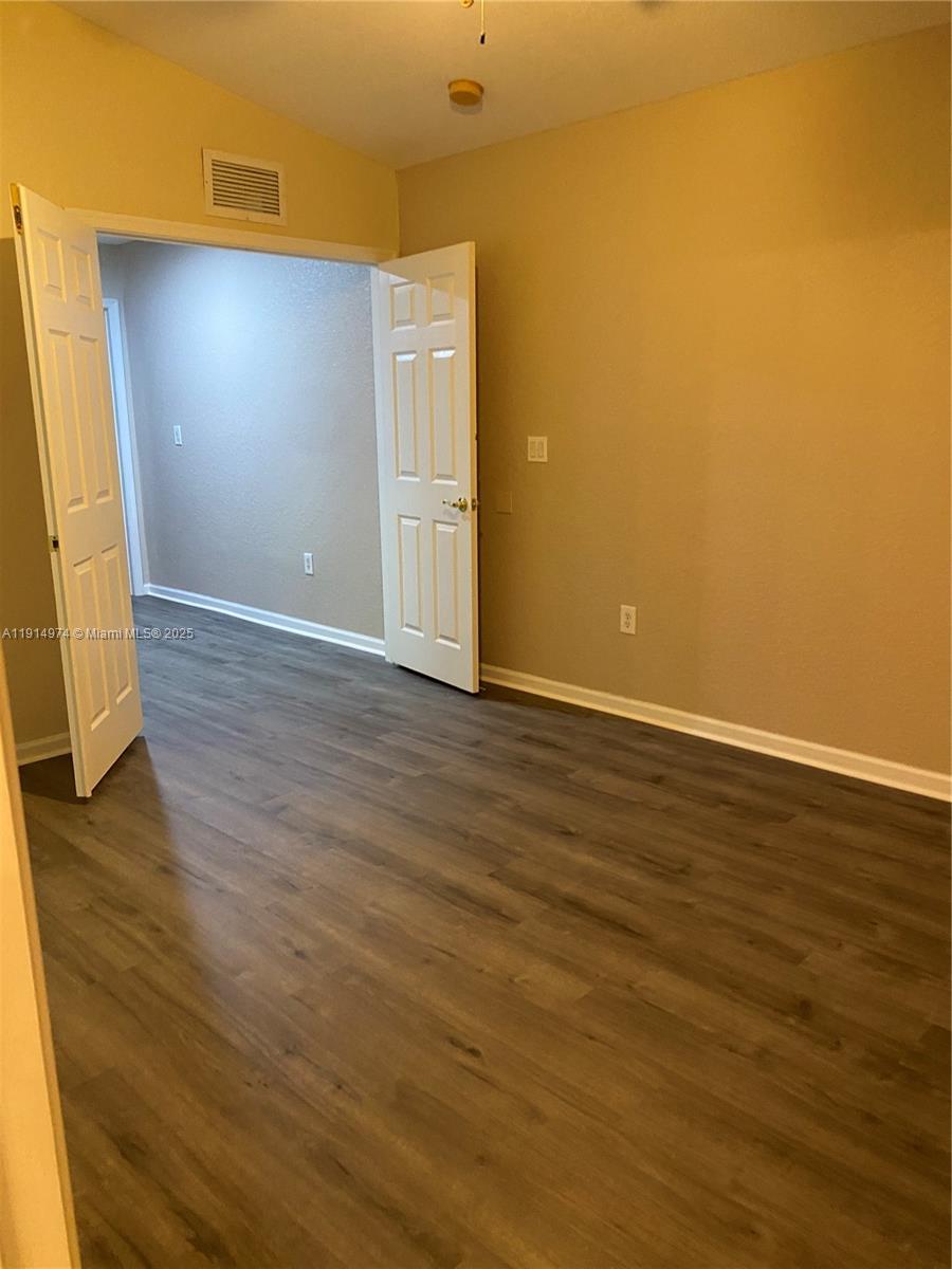 8395 Southwest 29th Street, Unit 102 Miramar, FL 33025 - Photo 17 of 20 a view of an empty room with wooden floor and a window