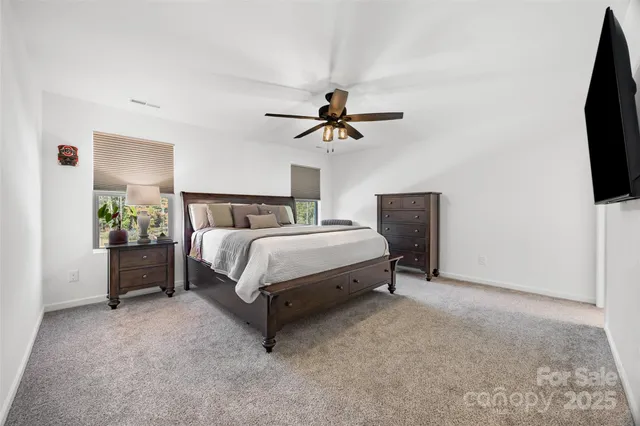 a bedroom with a bed and a flat tv screen on the dresser