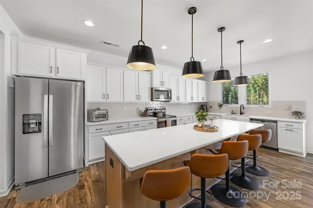 a kitchen with stainless steel appliances kitchen island a table a chair and a refrigerator