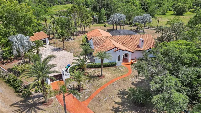 an aerial view of residential houses with outdoor space and trees