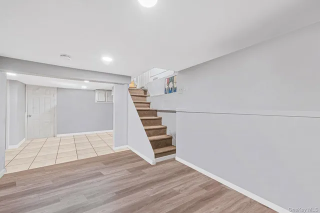 a view of an empty room with wooden floor and stairs