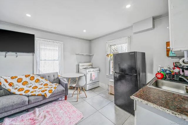 a living room with furniture and a refrigerator