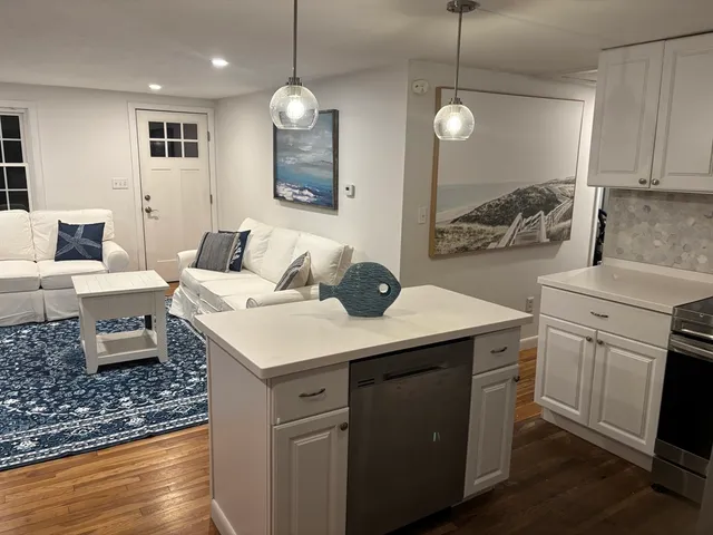 a kitchen with a sink dishwasher a stove and white cabinets with wooden floor