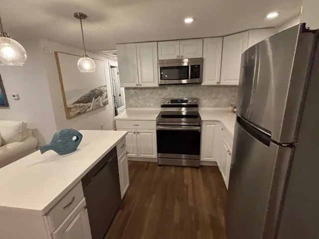 a kitchen with a refrigerator a sink and wooden floor