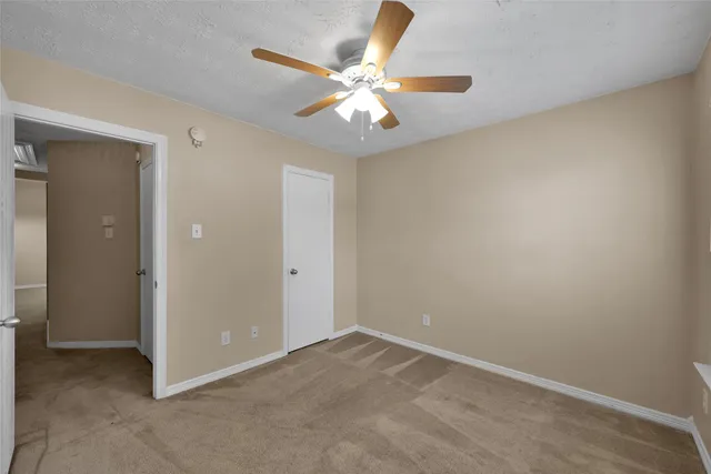 an empty room with closet and a ceiling fan