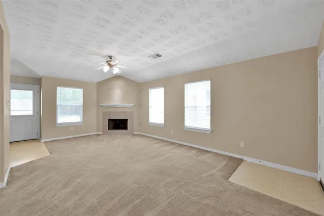 an empty room with windows and fireplace