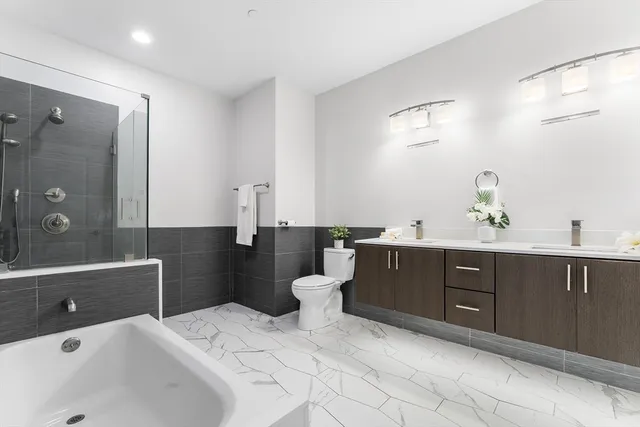 a spacious bathroom with a double vanity sink a toilet a mirror and shower