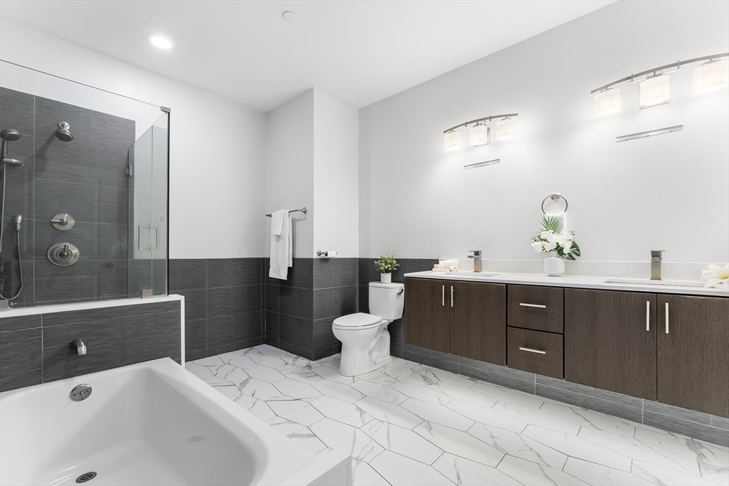 2 Cliveden Street, Unit 405E Quincy, MA 02169 - Photo 12 of 18 a spacious bathroom with a double vanity sink a toilet a mirror and shower