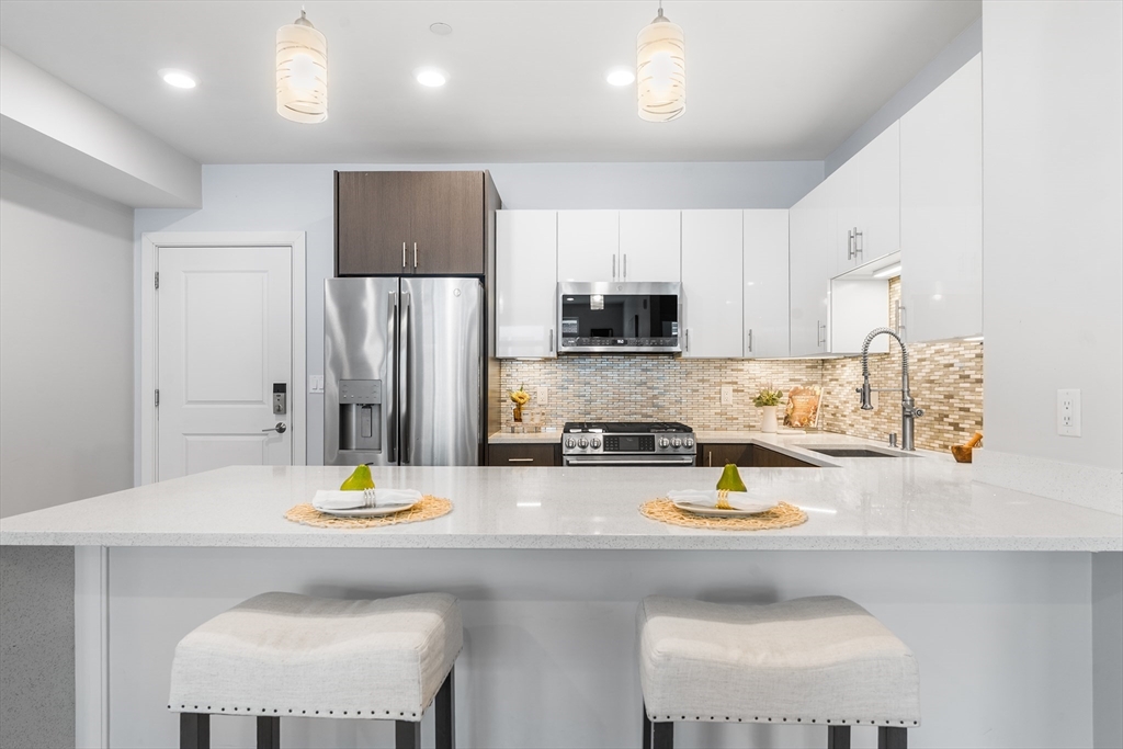 2 Cliveden Street, Unit 405E Quincy, MA 02169 - Photo 5 of 18 a kitchen with a sink a stove and chairs